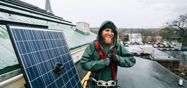 Ein Handwerker installiert ein PV Panel auf einem Dach.