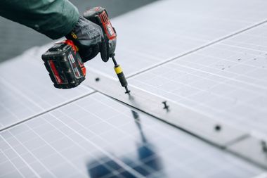 Nahaufnahme wie eine Person mit einem Akkuschrauber Solarpaneele befestigt.