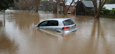 Ein Auto schwimmt in einer überfluteten Straße.