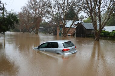 Ein Auto schwimmt in einer überfluteten Straße.