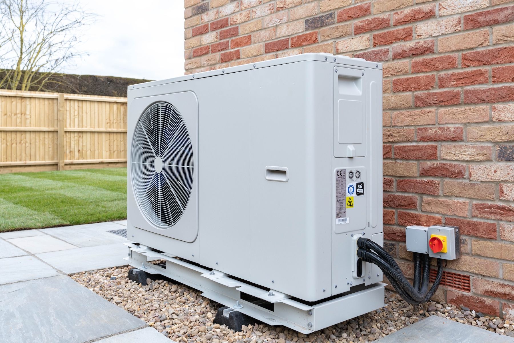 An air-source heat pump outside a brick home
