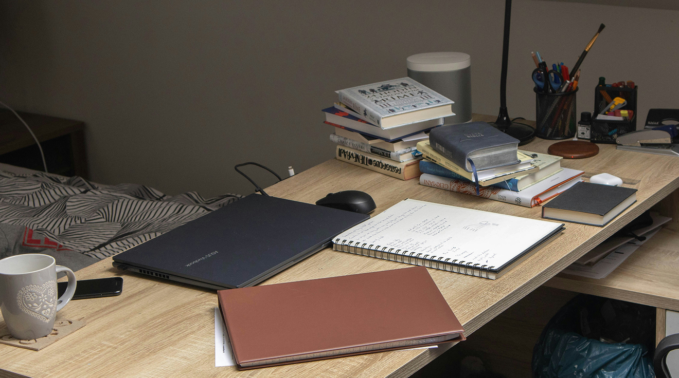 Skrivbord med böcker, en kaffekopp och en ihopslagen laptop.