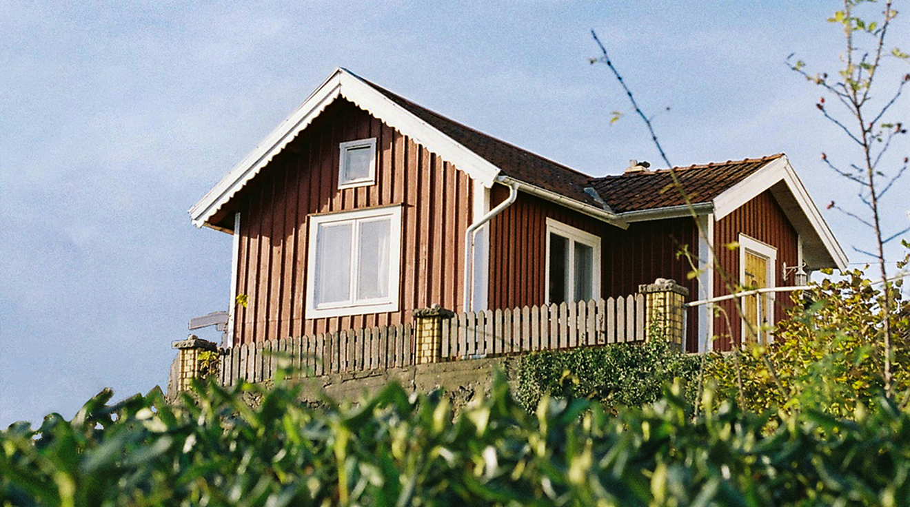 Röd stuga på en kulle.