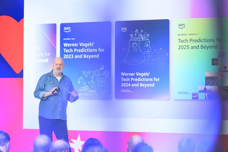 A speaker presents tech predictions for 2023 and beyond, with slides displaying titles and colorful graphics at a conference.
