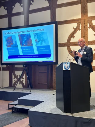 Bühne mit Redner am Pult vor Screen