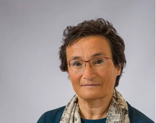 Virginia Dignum with short hair, wearing glasses, a teal top, and a patterned scarf, against a plain background.