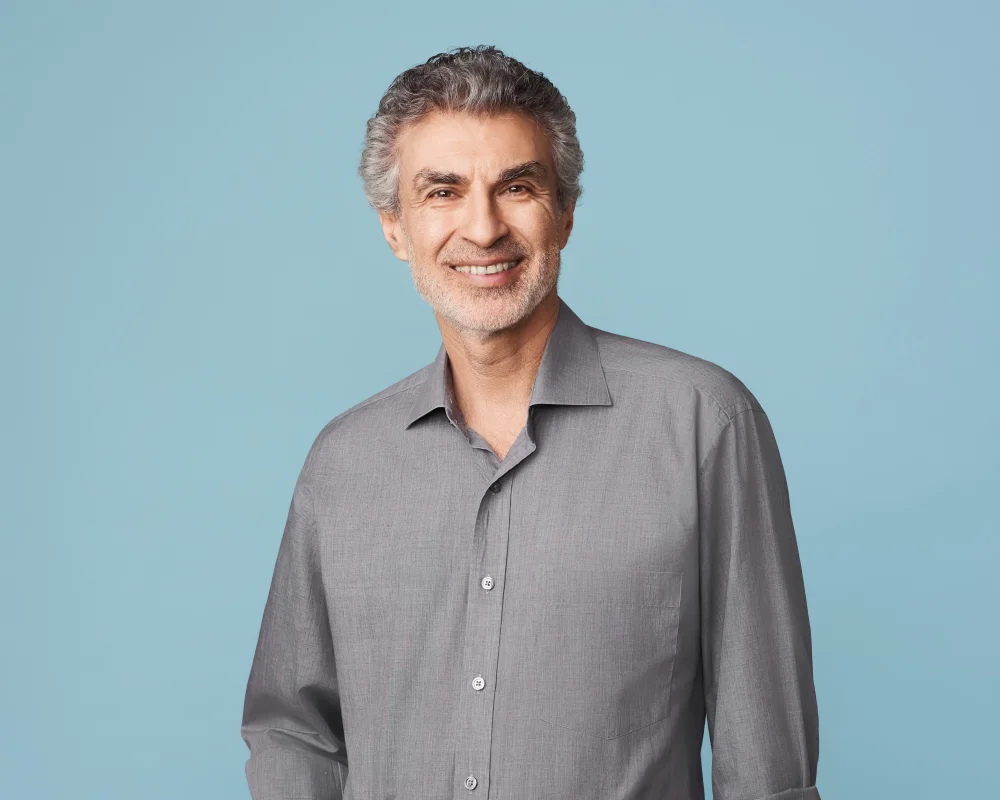 Prof. Bengio in grauem Hemd vor blauem Hintergrund