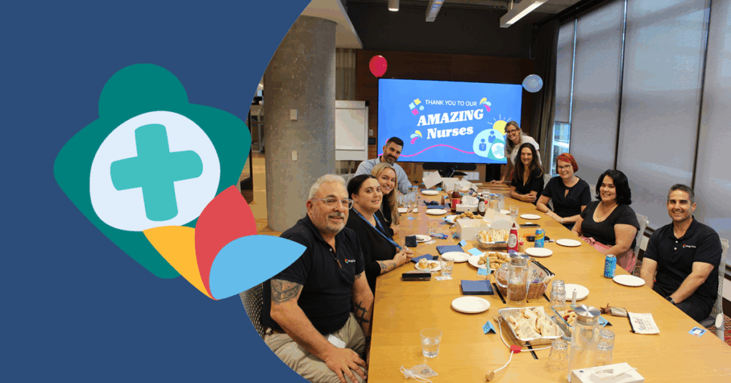 A group of people sitting around a conference table with a screen displaying "Amazing Nurses" in the background.