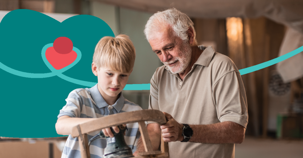Elderly man teaching a young boy woodworking in a workshop, with a heart graphic in the background.