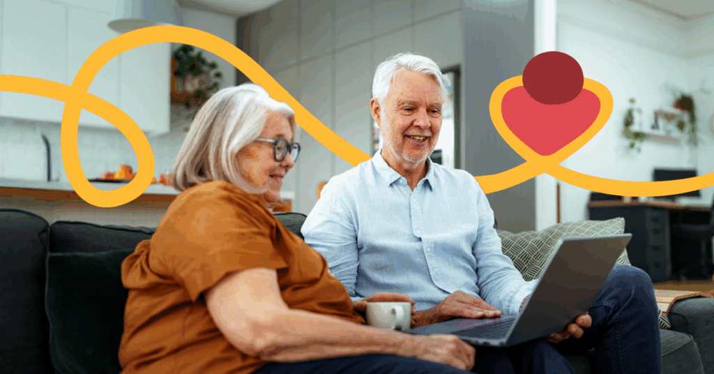 Elderly couple sitting on a couch, using a laptop, smiling. Bright, abstract yellow and red shapes in the background. Cozy living room setting.