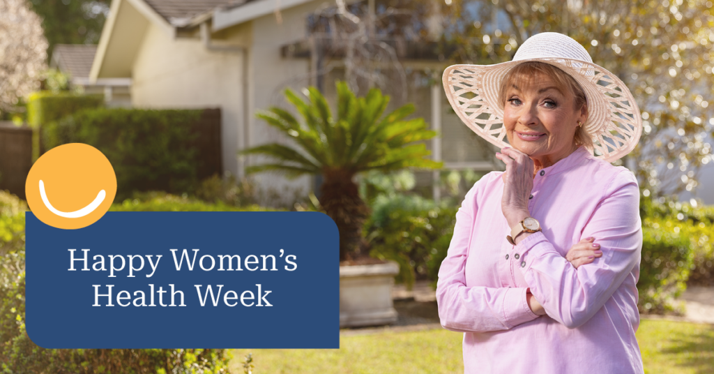 Woman in a white hat and pink shirt stands in a garden, smiling. Text reads "Happy Women's Health Week" on a blue banner.
