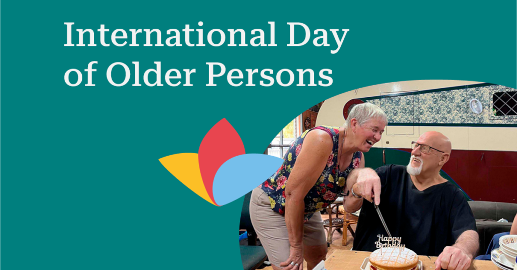 Elderly man and woman smiling, celebrating with a cake. Text reads "International Day of Older Persons" on a teal background with colorful petals.
