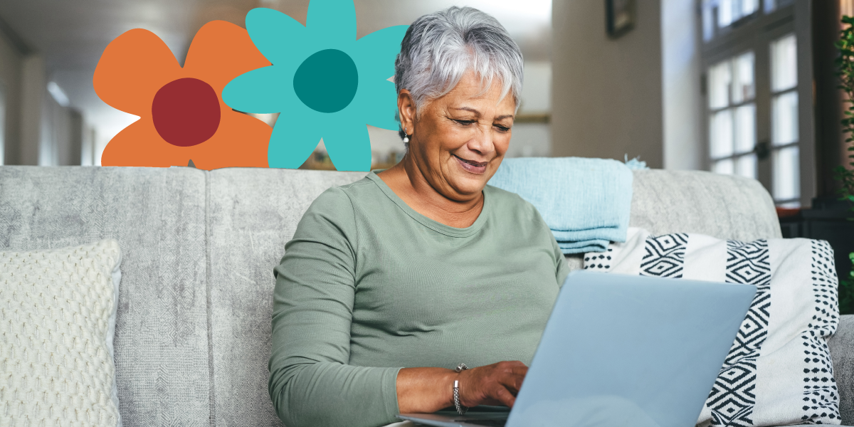 Elderly woman with short gray hair using a laptop on a sofa, surrounded by cushions, with colorful floral graphics in the background.