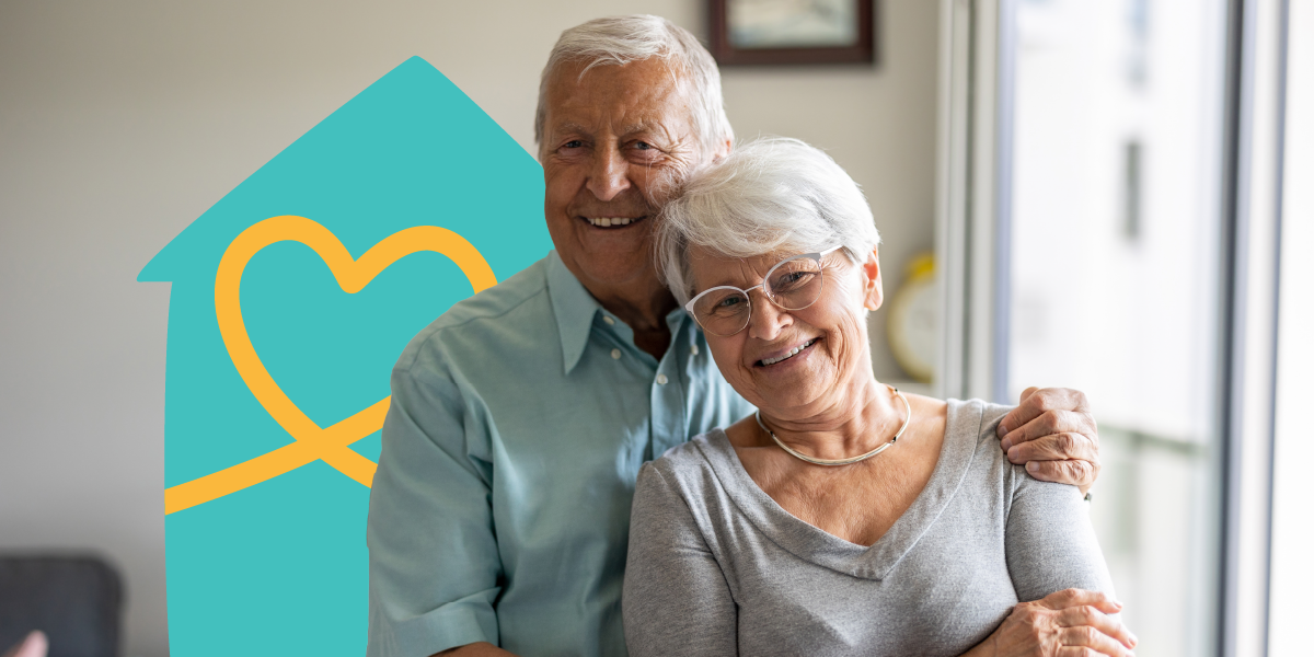 Smiling elderly couple embracing in a bright room, with a heart and house graphic in the background.