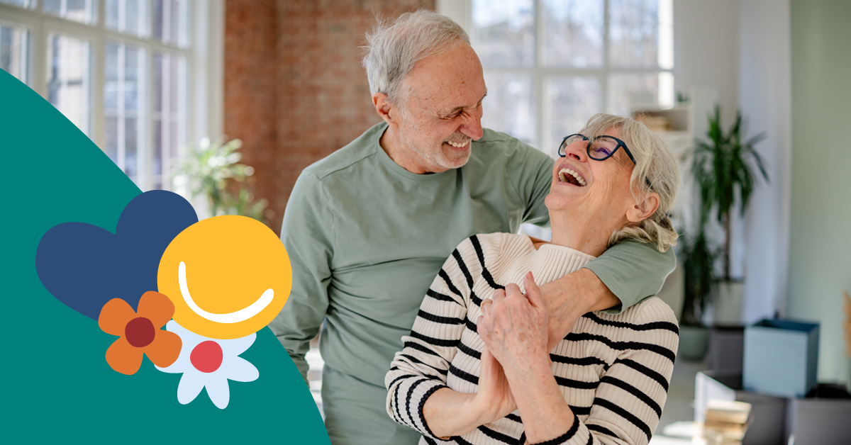 Elderly couple laughing together in a bright room, the man embracing the woman. Decorative graphics with a heart and smiley overlay the image.