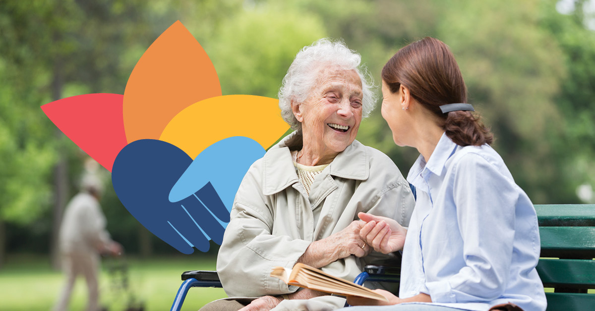 An elderly woman and a younger woman sit on a park bench, smiling and talking. A colorful graphic of hands is in the background.