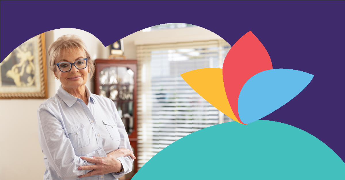 Smiling woman with glasses and short hair stands with arms crossed in a room, framed by a colorful abstract design on a purple background.