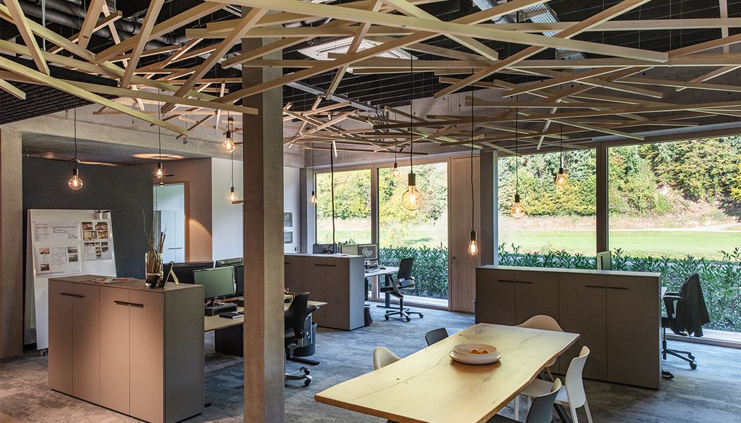 Offenes Büro mit kunstvoller Holzdecke und Pendelleuchten von SLV.