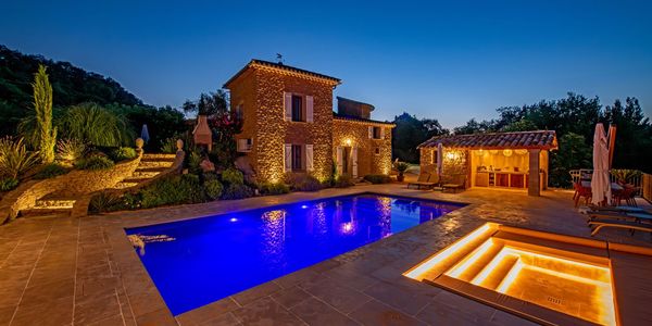 Beleuchtete Villa mit Pool, Terrasse und stimmungsvoller Außenbeleuchtung bei Nacht