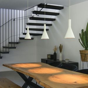 Modern dining area with a wooden table, pendant lights, and floating staircase. A potted cactus and decorative items adorn the corner.