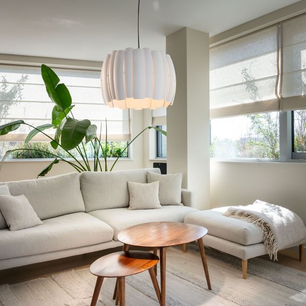 Helles Wohnzimmer mit weißem Ecksofa und dekorativer weißer Pendelleuchte
