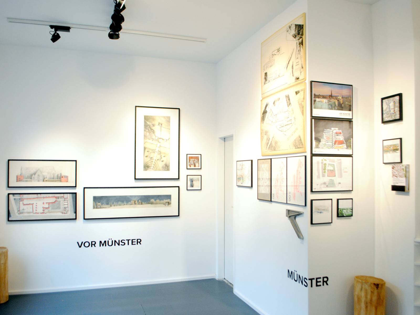 Ausstellungsraum mit Bildern an den Wänden, von Schienenstrahlern beleuchtet.