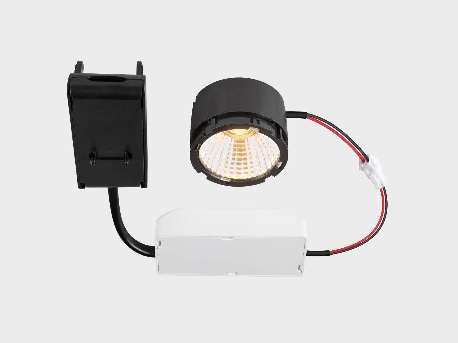 LED-Einbaustrahler mit schwarzem zylindrischem Gehäuse, der über rote und schwarze Kabel mit einer weißen Einbaudose und einem schwarzen Netzteil verbunden ist.