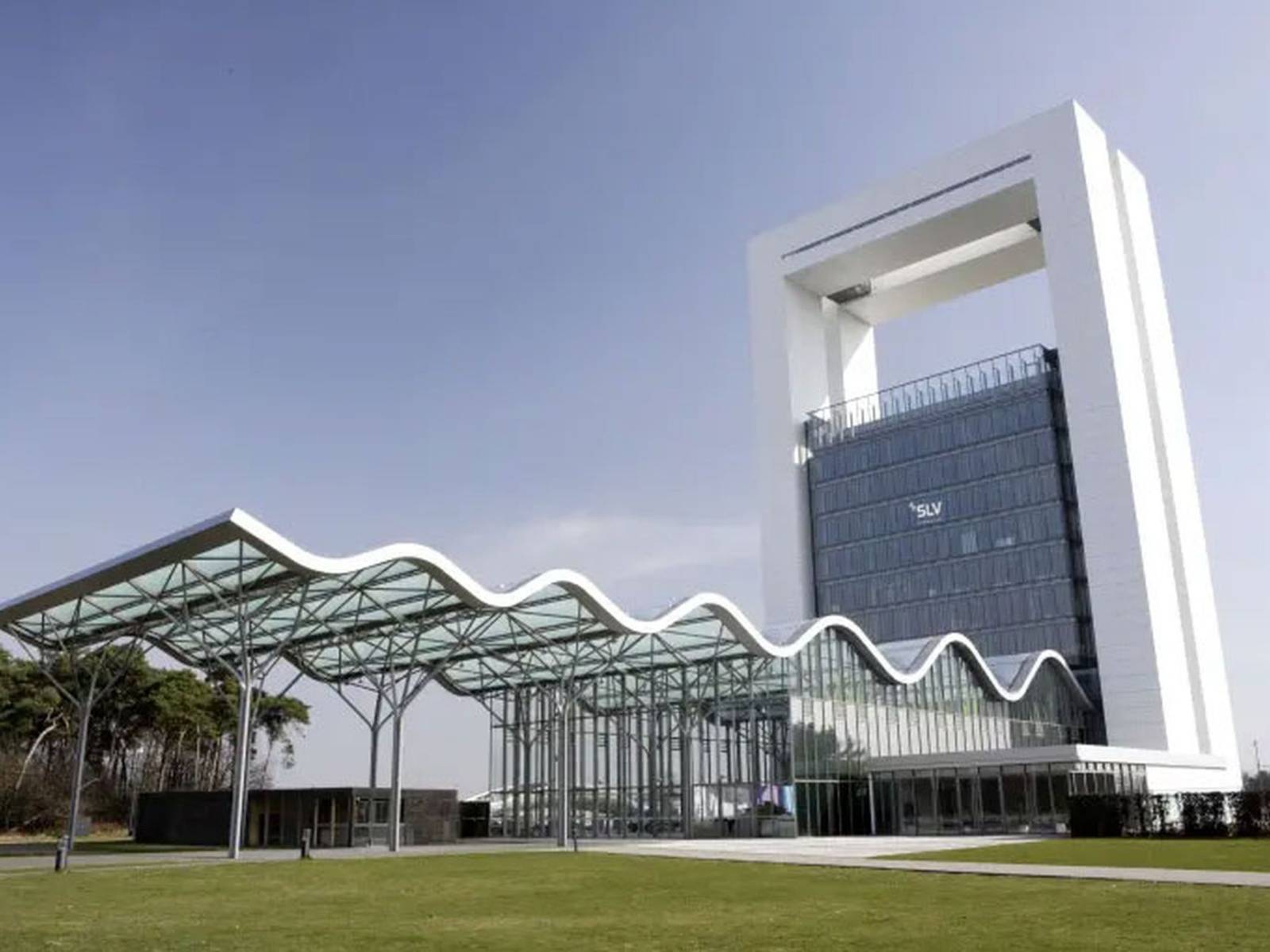 SLV Nederland bedrijfsgebouw: Modern SLV-kantoorgebouw met een opvallende witte architectonische structuur, een hoge glazen toren en een golvende glazen overkapping boven het entreegebied