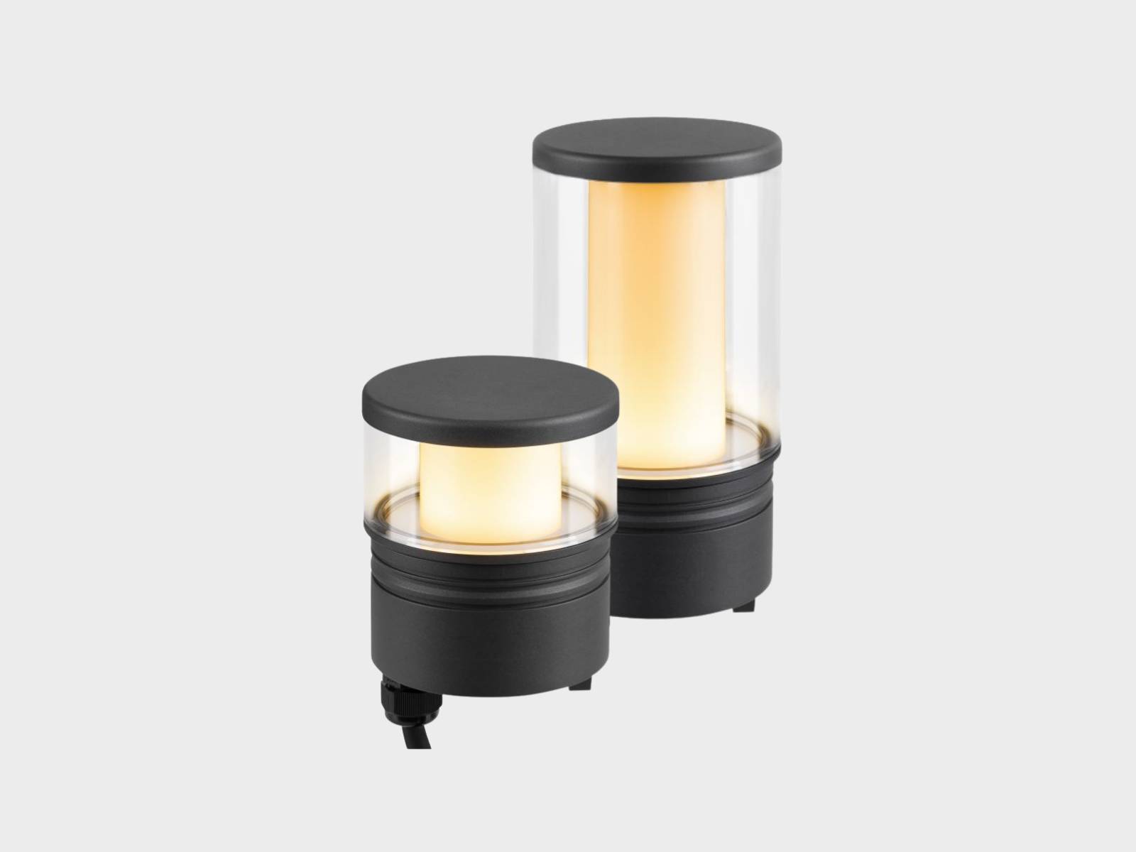 Zwei schwarze, zylindrische M-POL Leuchtenköpfe mit transparenten Glas und rundumstrahlenden Licht.