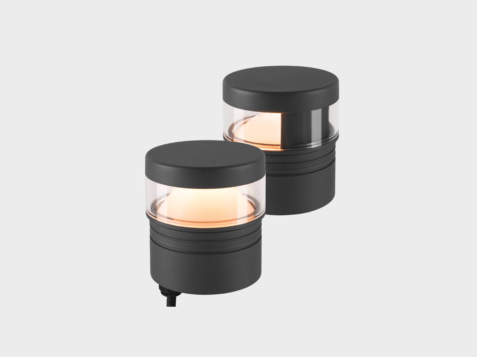 Two black cylindrical LED lights with transparent bands, emitting a warm glow, placed against a plain gray background.