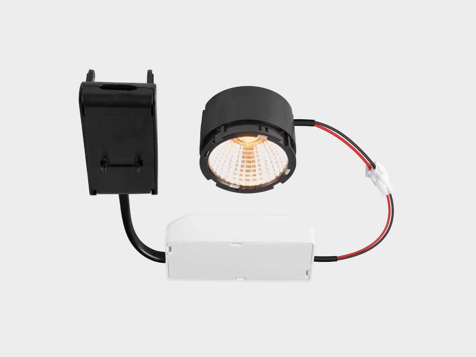 LED-Einbaustrahler mit schwarzem zylindrischem Gehäuse, der über rote und schwarze Kabel mit einer weißen Einbaudose und einem schwarzen Netzteil verbunden ist.