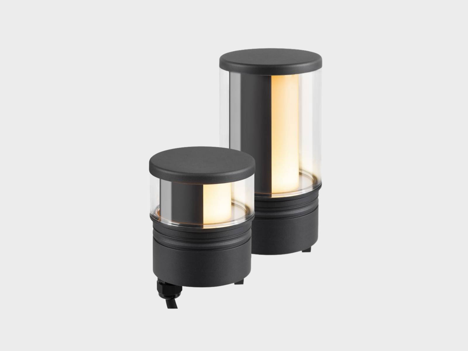 Zwei schwarze, zylindrische M-POL Leuchtenköpfe mit transparenten Glas und zur Hälfte gefiltertem Licht.