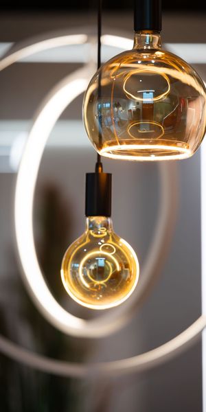 Zwei dekorative LED-Filamentlampen mit bernsteinfarbenem Glas vor leuchtenden Ringen