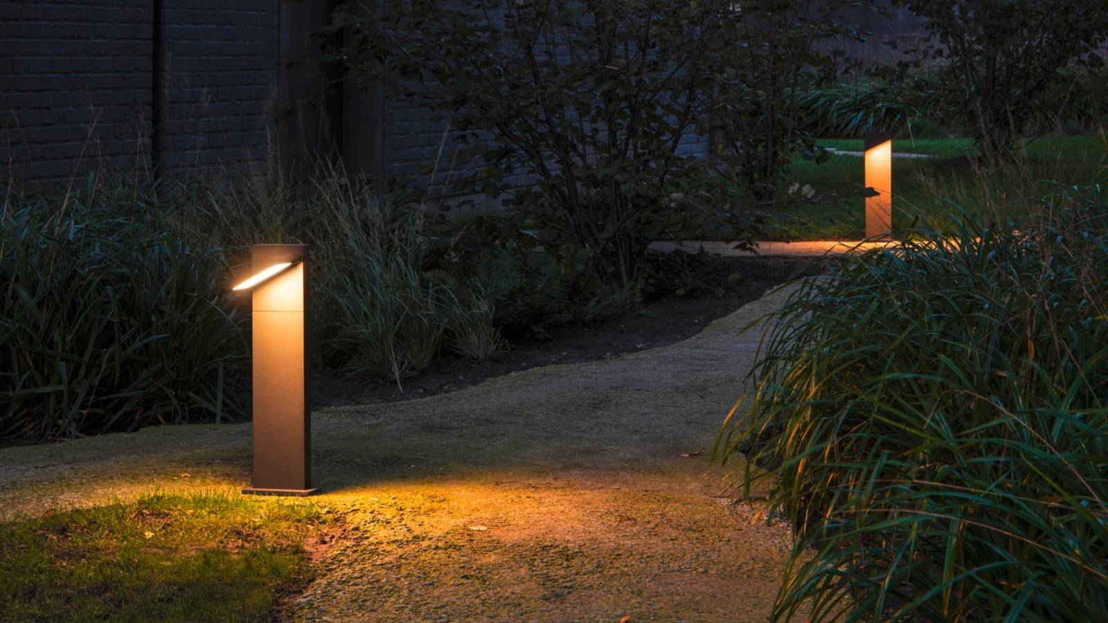 Flache Gartenwegleuchten aus Edelstahl setzen die Pflanzen im nächtlichen Außenbereich in Szene.