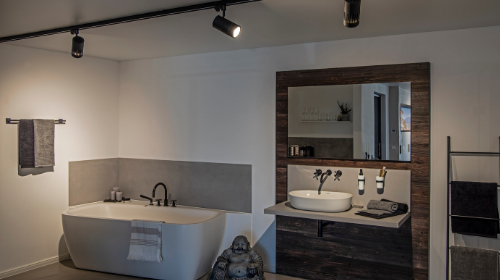 Modernes Badezimmer mit freistehender Badewanne, wandhängendem Waschbecken, großem Spiegel und minimalistischer Einrichtung in neutralen Farbtönen.