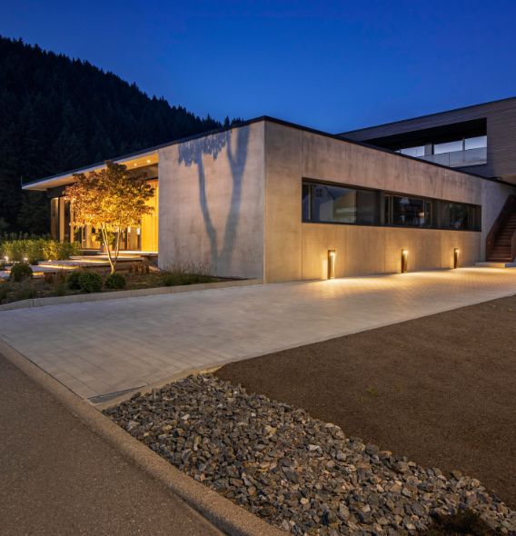 Eingangs- und Wegebeleuchtung von SLV, die Betonkomplex in warmweißes Licht in der Dämmerung hüllen.