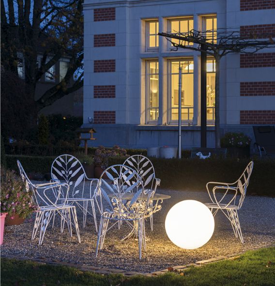 Rundliche SLV Leuchte bei Sitzgruppe in Garten.