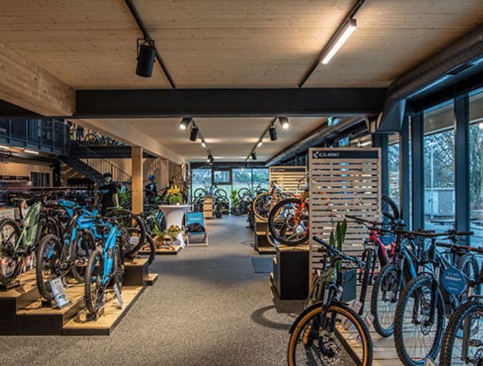 Verkaufsraum eines Bike-Shops mit zahlreichen Fahrrädern auf Podesten und einer Deckenbeleuchtung aus Stromschienen und LED-Lichtbändern