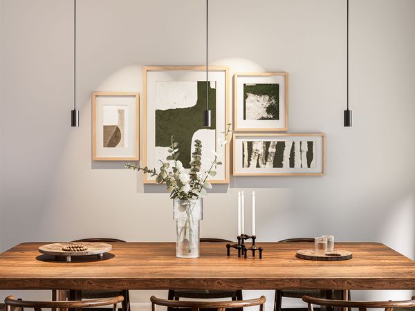 Moderner Essbereich mit drei schlanken schwarzen Pendelleuchten über einem Holztisch
