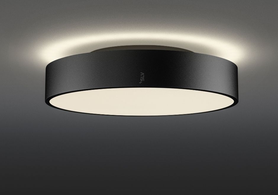 A sleek, modern black ceiling light fixture with a circular design, softly illuminated around the edges on a dark background.