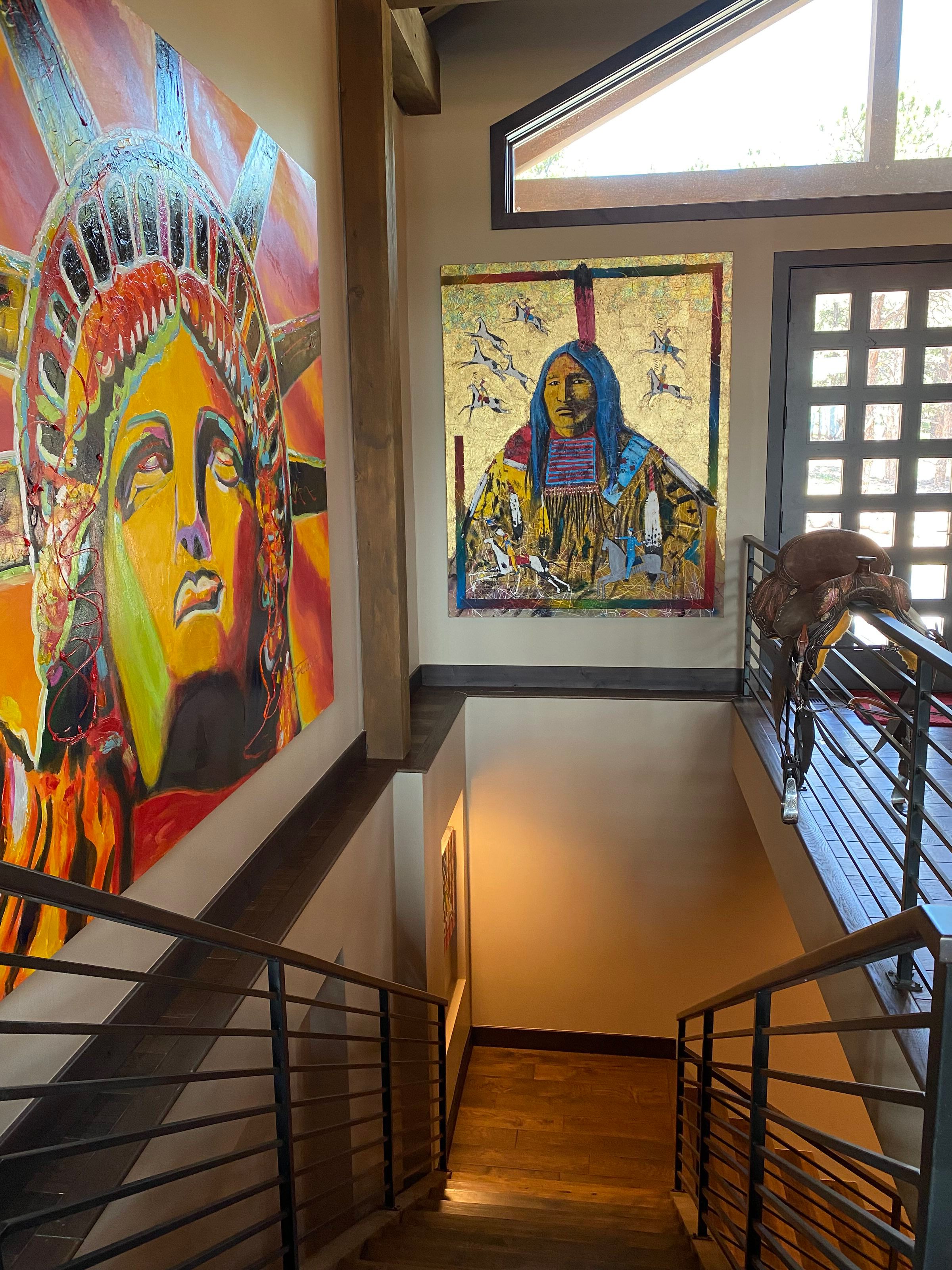Staircase with colorful paintings of the Statue of Liberty and a Native American, next to a sculpture of an eagle on the railing.