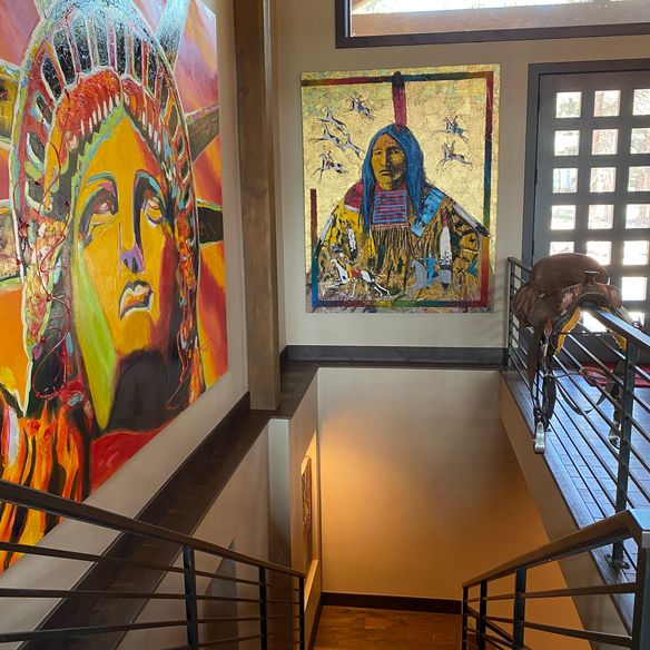 Staircase with colorful paintings of the Statue of Liberty and a Native American, next to a sculpture of an eagle on the railing.