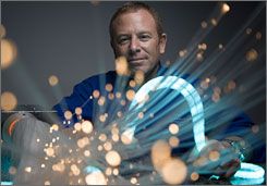 Brett Kingstone in a blue shirt surrounded by glowing fiber optic cables and bokeh lights, creating a futuristic and dynamic atmosphere.