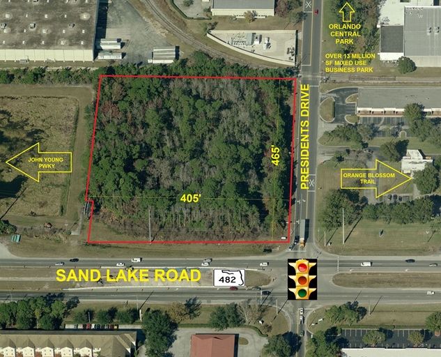 Aerial view of a wooded plot outlined in red at the intersection of Sand Lake Road and President's Drive, with surrounding roads labeled.