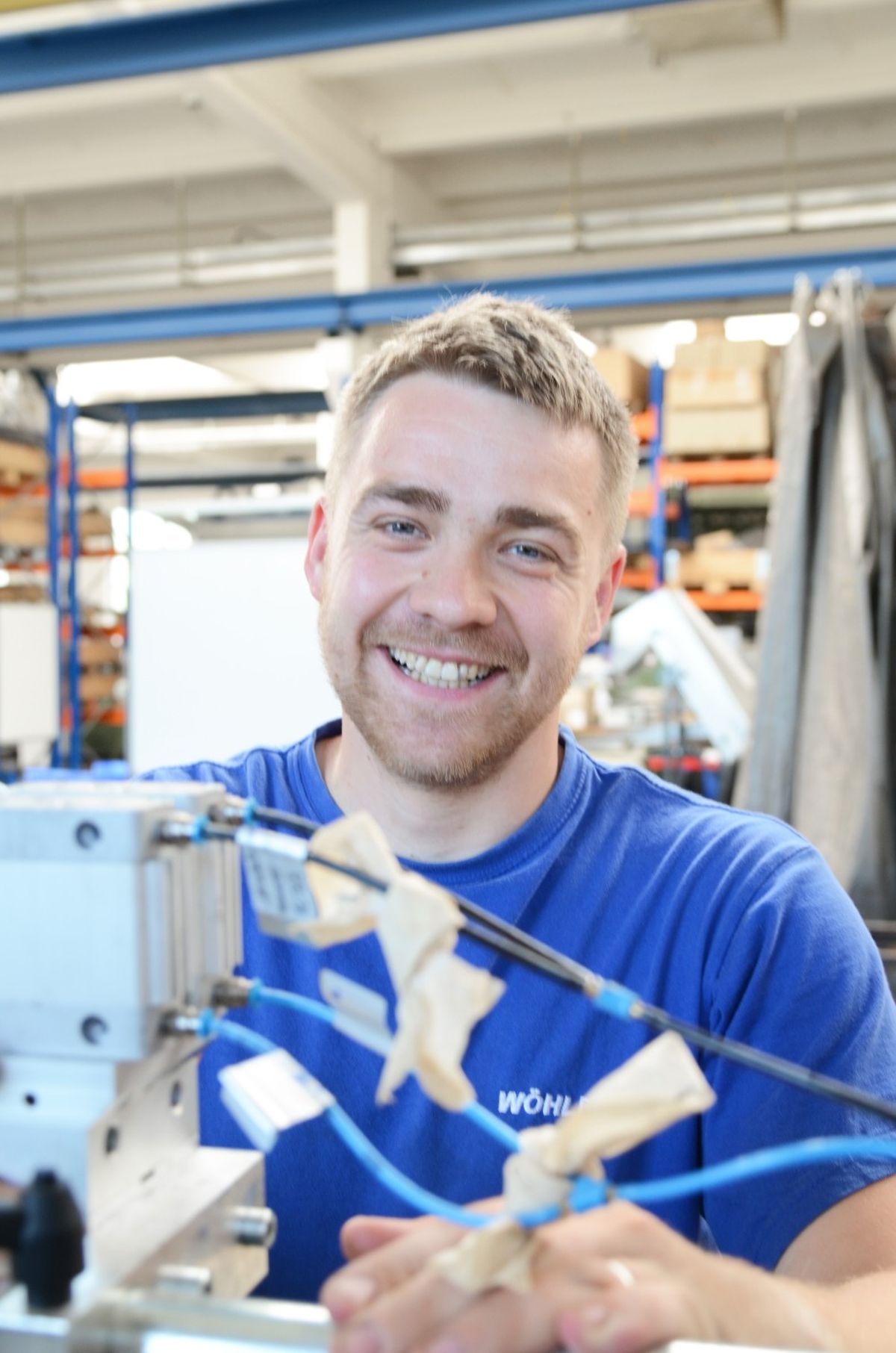 Un tecnico aziona un sistema dotato di linee pneumatiche e componenti montati. Lavora in un ambiente di produzione industriale incentrato sull'assemblaggio di precisione e sull'automazione.