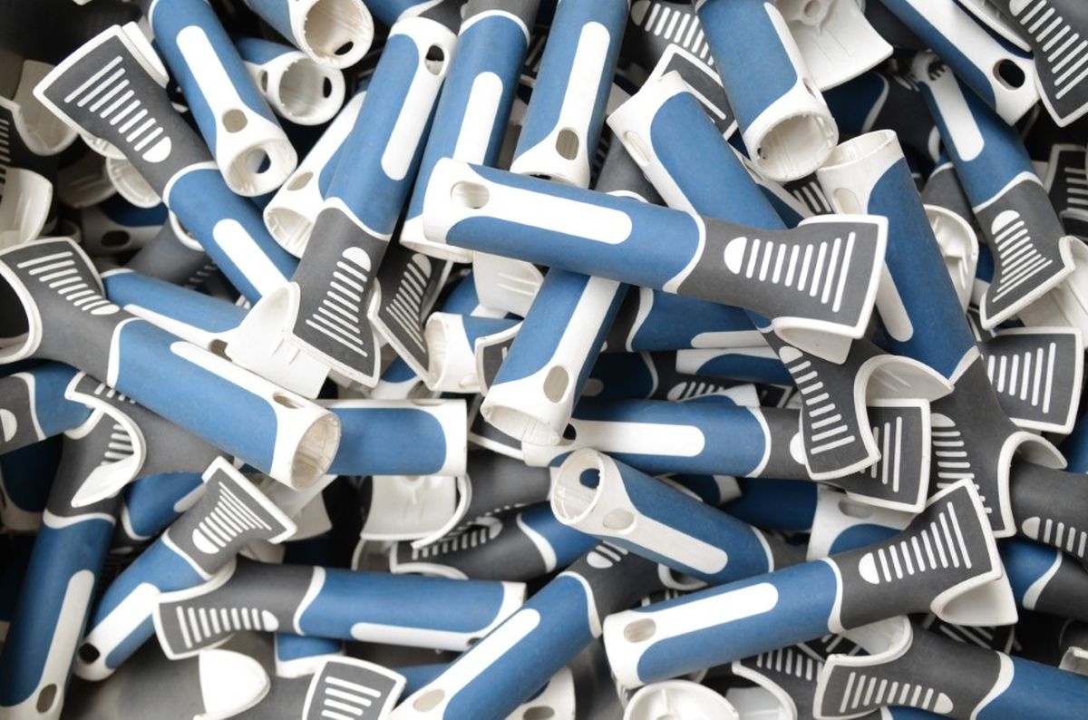 Numerosi portaspazzole in plastica blu e grigia sono impilati in un contenitore di produzione. I componenti sono preparati per la lavorazione automatizzata all'interno di una linea di produzione industriale.