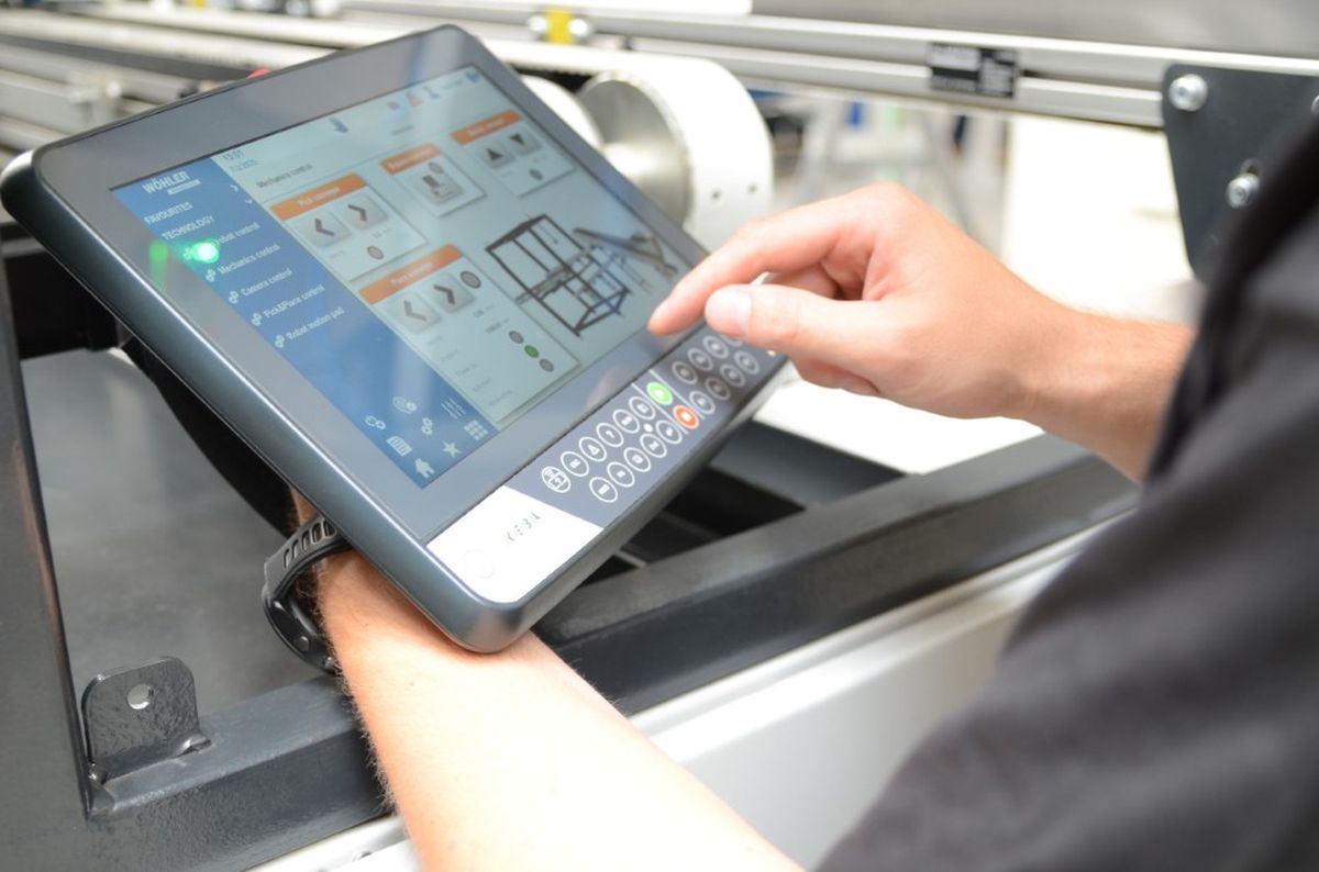 Primo piano del pannello HMI KeTop Safe Wireless con funzionamento touchscreen in un ambiente macchina. L'interfaccia utente grafica mostra le opzioni di controllo per gli assi e le funzioni di movimento.