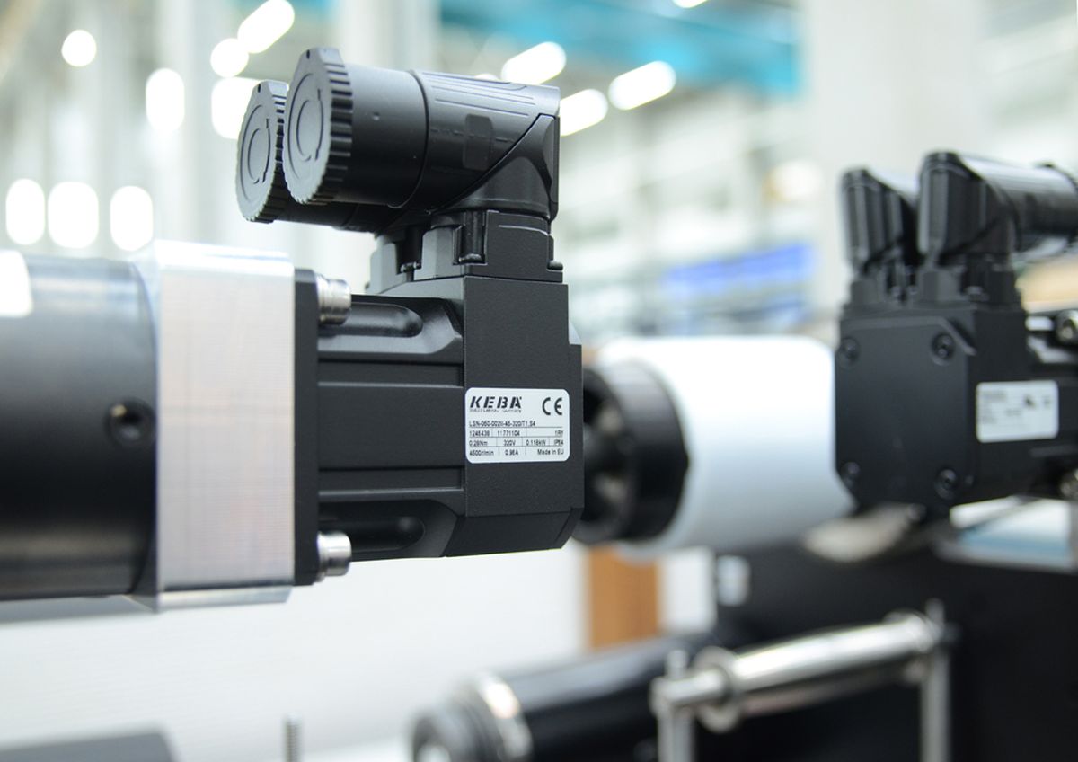 Nahaufnahme von Industriemaschinen mit Fokus auf einem schwarzen Motorteil mit der Aufschrift „KEB“ in einer Fabrikumgebung.