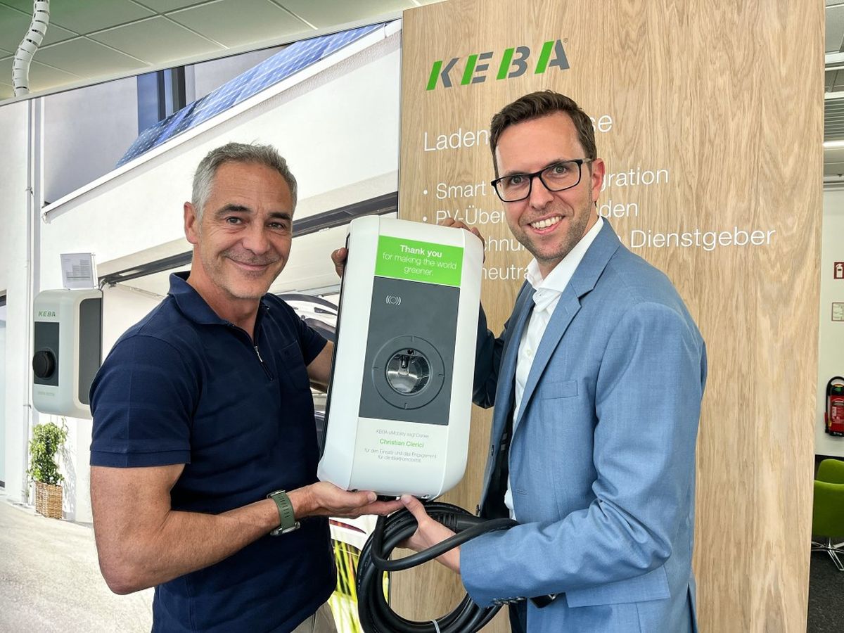 Christian Clerici hält die personalisierte KEBA Wallbox mit einem KEBA-Repräsentanten.