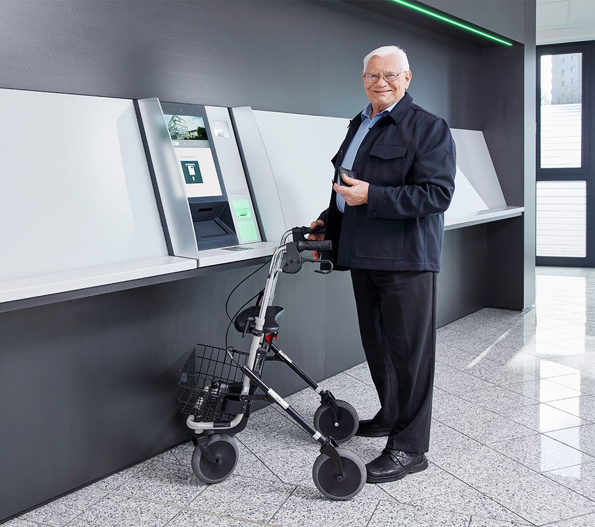 Älterer Mann mit Rollator vor unterfahrbarem KEBA Cash Recycler